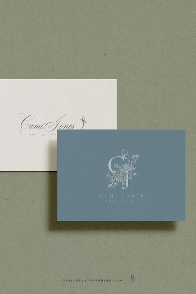 Luxury business card design for Cami Jones Portraits showcasing a soft blue background, floral crest monogram, and elegant serif typography.